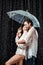 side view of romantic couple in white shirts standing under umbrella under raindrops