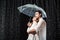 side view of romantic couple in white shirts standing under umbrella under raindrops