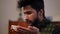 Side view satisfied young Middle Eastern man smelling small plate in hands smiling. Close-up portrait of handsome