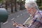 Side view of senior man with beard and white hair reading a message on his cellphone. Elderly person and modern technology.