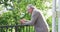 Side view of senior man leaning on railing while using smart phone in balcony