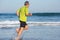 Side view of senior man running barefoot along seashore