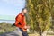 Side view of a senior runner man leaning on fence while testing exercise in a mobile phone outdoors in a sunny day