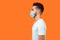 Side view of serious handsome brunette man with surgical medical mask standing with hands down and looking left, empty copy space