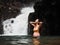 Side view of sexy asian pregnant woman in bikini standing in tropical waterfall. female touching long hair in water. Pregnancy rel