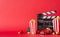 Side view shot of table adorned with popcorn boxes, festive baubles, miniature retro car, clapperboard against red wall background