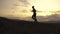 Side view on silhouette of african american athlete jogging on sunset on the mountain peak. Cloudy sky background