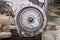 A side view of a silver gearbox taken from a car in a vehicle repair workshop.