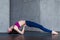 Side view of skinny young yogini standing in yoga backbend pose on mat in studio