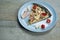 side view of Slice of black dough pizza with ingredients on blue plate on stone anthracite background.