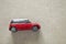 Side view of small bright red metal simple child toy car on light beige canvas cloth copy space background