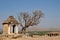 Side view of small historical building and the frangipani tree against the background of mountains and ancient ruins on sunny day