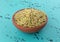 Side view of a small terracotta bowl filled with rosemary whole leaf on a tabletop