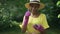 Side view smiling African American female gardener holding green seedling in pink gloves turning gesturing thumb up