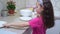 Side view of smiling little preteen girl washing dishes, wiping clean plates with cloth on table in kitchen. Cleaning.