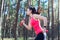 Side view of sportive attractive girl working out with dumbbells, training in the forest. Fitness, sport, lifestyle