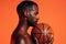 Side view of sportsman with basket ball under his chin against orange background in studio