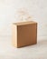 Side view of square closed Kraft cardboard box on a white background