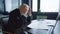 Side view of stressed overburdened Caucasian middle aged man sitting in office sighing taking off eyeglasses. Medium