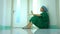 Side view of stressed and overworked female doctor medical worker surgeon sitting on the floor near the operating room in hospital