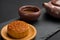 Side view studio shoot of traditional Chinese mooncake with tea and teapot on black