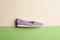 Side view of stylish women\\\'s gray leather slip-on with embossing and perforation isolated on a beige-green background