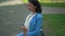 Side view successful pregnant businesswoman in elegant blue suit stroking belly dreaming sitting on bench in city. Happy