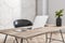 Side view on sunny stylish home workspace with eco interior design: laptop and digital tablet on wooden table, tree branch in