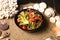 Side view of Thai Salad with beef medallions and fresh vegetables in black plastic Food Delivery bowl with sea shells and stars on