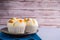 Side view of Thai steamed cupcakes topped with dry fruit on a plate placed on a blue cloth with wooden wall background.