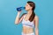 Side view thirsty athletic woman in white sportswear drinking spring water from bottle, restoring water balance after exhausted