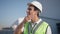 Side view of thoughtful handsome professional Middle Eastern man adjusting hard hat standing at warehouse outdoors with