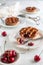 Side view of three individual cherry pies white plates with one pie cut open with a fork  white background and cherries around