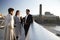 Side view of three millennial business colleagues stand talking on Millennium Bridge, London, selective focus