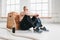 Side view of tired strong man sitting on box at gym