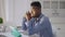 Side view of tired young man holding head in hands sitting at table with tablet in home office. Portrait of stressed