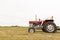 Side view of a tractor standing in a crop field. The day is cloudy. Concept of agriculture and rural life