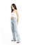 Side view of trendy summer girl in jeans looking away with hands behind back.