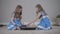 Side view of two concentrated caucasian sisters playing chess. Portrait of focused twins sitting in front of each other