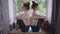 Side view two identical young women sitting on windowsill back to back thinking. Wide shot argued stubborn Caucasian