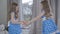 Side view of two little girls fighting for a gift. Brunette twins in elegant blue dresses holding and pulling present