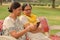 Side view of two Senior Indian woman working on mobile phone/tablet, experimenting with technology on a red park bench in an