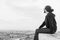 Side view unidentified young man in casual clothes and glasses sits on the high rock and looks at beautiful desert