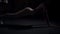 Side view unrecognizable fit slim woman working out in plank position in darkness. Wide shot confident motivated