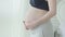 Side view of unrecognizable pregnant woman caressing naked belly. Young Caucasian woman stroking abdomen standing in