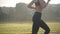 Side view of unrecognizable sportswoman jogging in sunrays outdoors. Slim sportive Caucasian woman running in sunlight