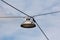 Side view of vintage old style large round street lamp within metal casing suspended with electrical wires above street crossroads