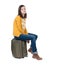 Side view of walking woman in cardigan sits on a suitcase.