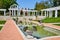 Side view of water pool along stone path leading to gorgeous outdoor wedding spot with pergola