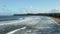 Side view of waves and surf rolling towards the beach and pier at Hanalei on Hawaiian island of Kauai